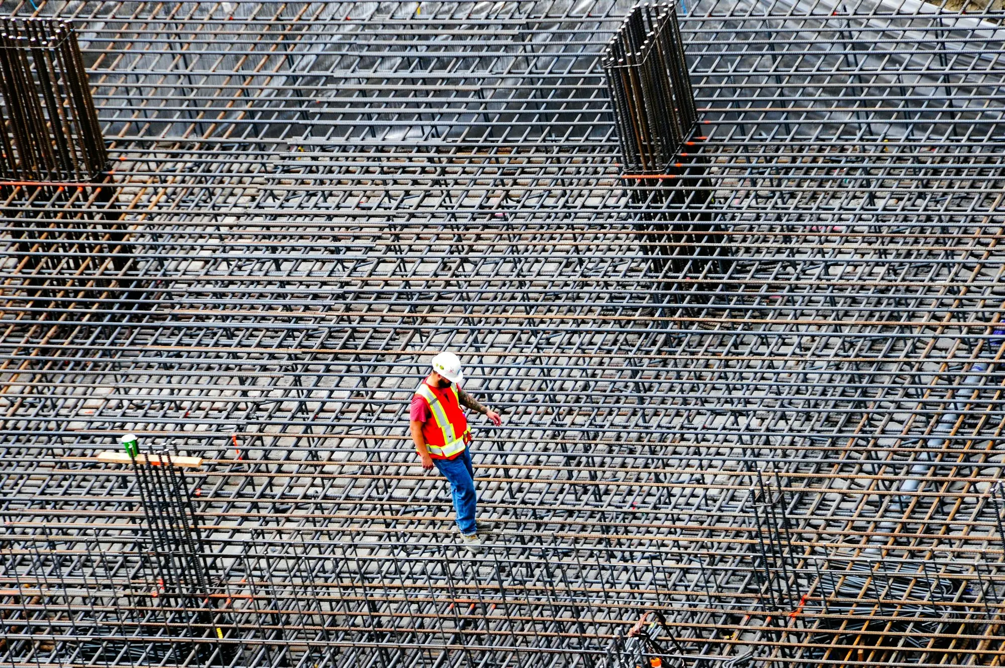 Builder in hi-vis checking steel reinforcement on a large construction site