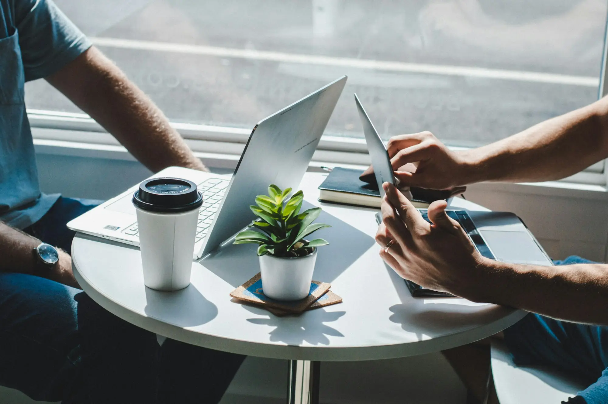 Marketing team planning a campaign around a café table with laptops