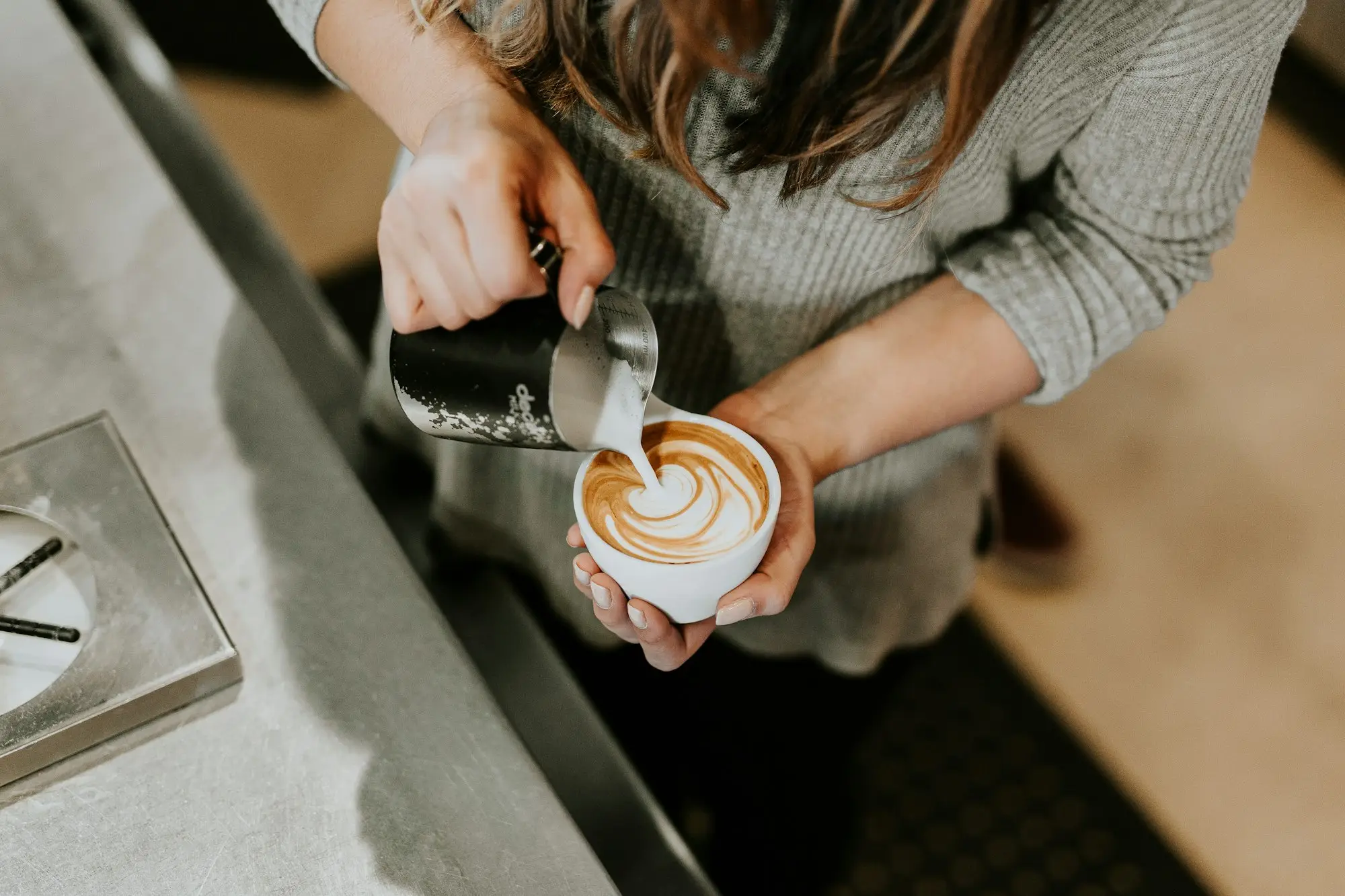 New barista learning to pour latte art on the first day at a café